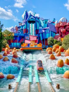 an amusement park with water slides and large orange balls in the river, surrounded by trees