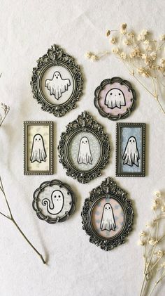 six framed pictures with ghost faces in them on a white wall next to dried flowers