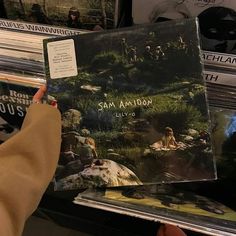 someone is holding up an album in front of some records