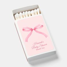 a box of matches with a pink bow on the front and white tips in the back