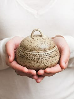 a person holding a teapot in their hands with speckles on the lid