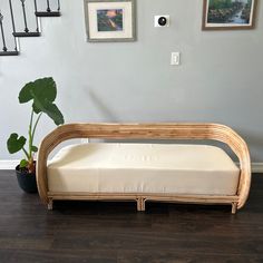 a wooden bench sitting on top of a hard wood floor next to a potted plant