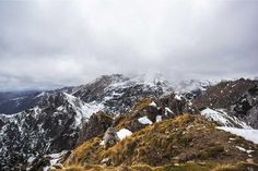 the mountains are covered in snow and grass