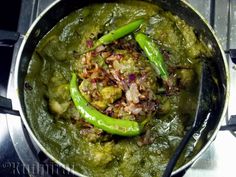 some green peppers and other food in a pot on the stove top with spoons