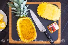 a pineapple cut in half on top of a cutting board with a knife next to it