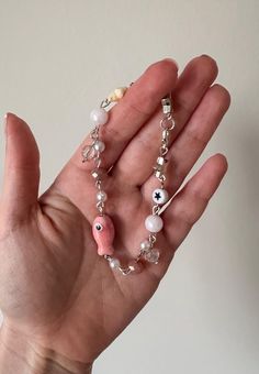 a person holding their hand in the air with some beads and charms attached to it