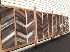 a wooden fence made out of strips of wood on the side of a white house