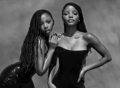 two beautiful women standing next to each other posing for a black and white photo together