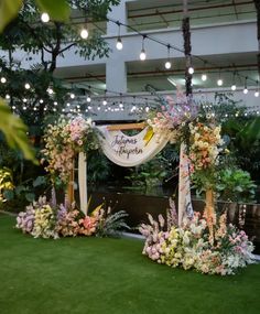 an outdoor wedding setup with flowers and greenery on the grass in front of it