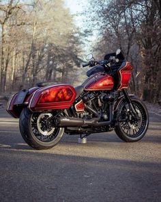 a red and black motorcycle parked on the side of a road in front of trees