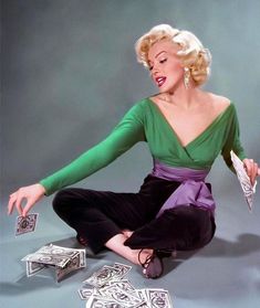 a woman sitting on the ground with money in front of her and playing cards around her