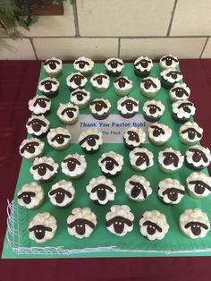 cupcakes with black and white sheep on them sitting on top of a green table