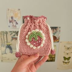 a crocheted pink purse with a heart on the front is held up by someone's hand