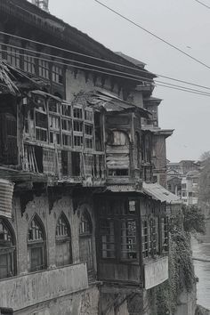 an old building with many windows and balconies on the top floor next to a body of water