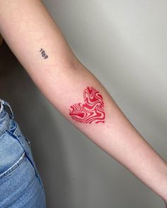 a woman's arm with a red and white tattoo design on the left forearm