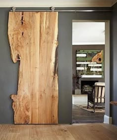 a wooden door is open in a room with gray walls and wood flooring, along with pictures on the wall