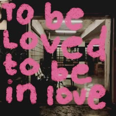 the words to be loved by someone in love are painted on a glass door with pink paint