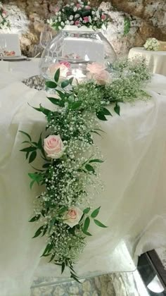 the table is covered with white flowers and greenery