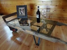 a glass table with two wine glasses and a bottle on it in front of a wood paneled wall