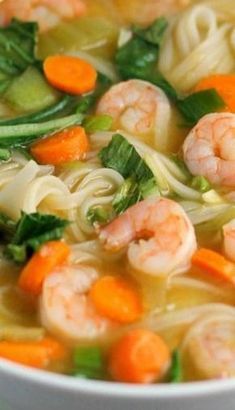 a white bowl filled with shrimp, noodles and vegtables in broth