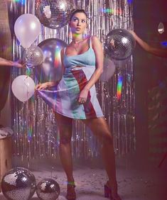 a woman standing in front of balloons and disco balls