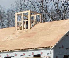 a house under construction with the roof being framed by scaffolding and tools on it