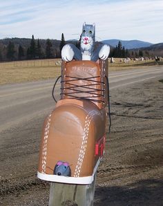 a cat sitting on top of a mailbox in the shape of a horse drawn carriage