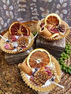 three oranges with pine cones and berries on them