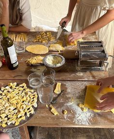 some people are making food on a table with wine bottles and other items in front of them