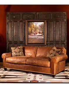 a leather couch sitting in front of a painting on the wall next to a rug