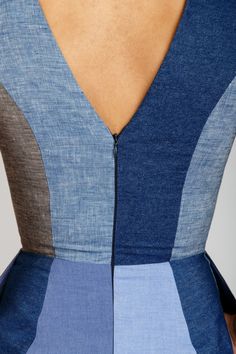 the back of a woman's blue and grey dress with an open neckline