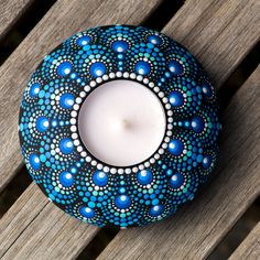 a lit candle sitting on top of a wooden table next to a blue and white vase