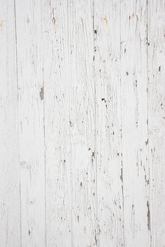 an old white painted wooden wall with peeling paint on the side and wood grains