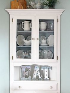 a white china cabinet with glass doors and letters