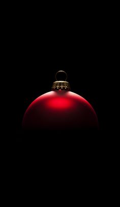 a red ornament on a black background in the dark with light shining through it