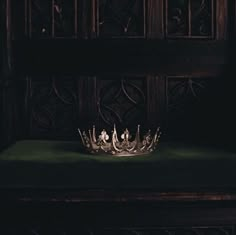 a crown sitting on top of a green cloth covered bench in front of a wooden paneled wall