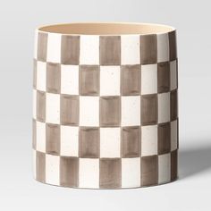 a white and brown checkerboard mug sitting on top of a table