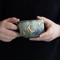 a person holding a cup with the moon and stars on it