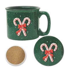 two green mugs with candy canes on them next to a small white bowl