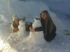 two girls are building a snowman in the snow