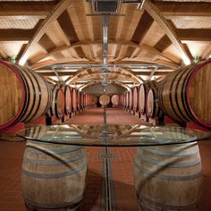 the inside of a wine cellar with several wooden barrels and glass tables in front of them