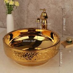 a bathroom sink with a golden bowl and gold faucet