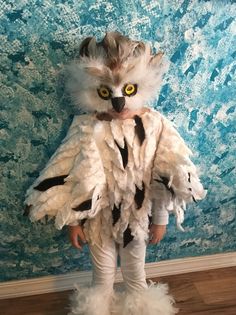 a small child dressed up like a cat with feathers on it's body and eyes