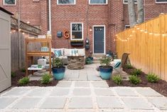 an outdoor patio with seating and potted plants on the side, next to a brick building