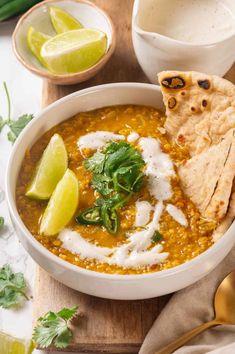 a bowl of soup with tortilla, sour cream and cilantro on the side