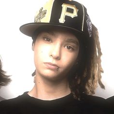 a young man wearing a baseball cap with dreadlocks in front of his face