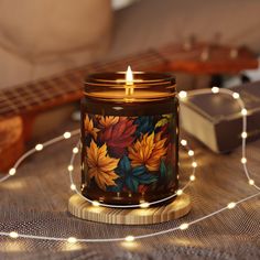 a lit candle sitting on top of a table next to a string of lights and a guitar