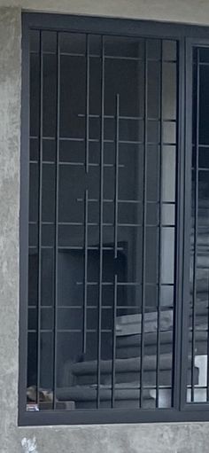 a cat sitting on the ledge of a window sill next to a wall with bars