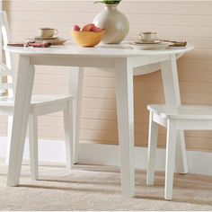 a white table with two chairs and a bowl of fruit on the plate next to it