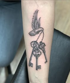 a tattoo on the arm of a woman with keys and a bird flying over it